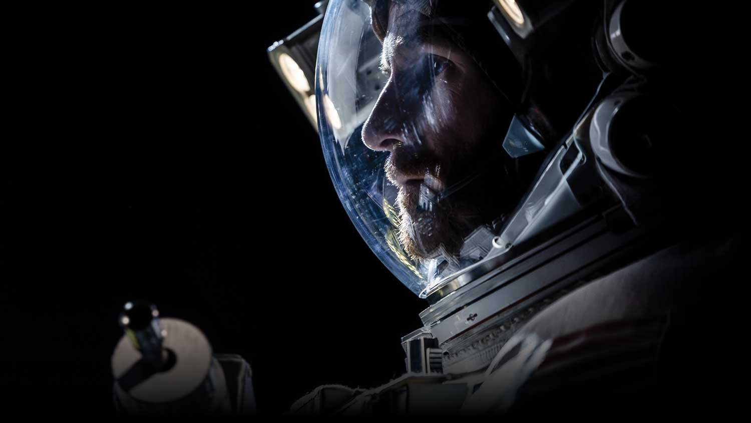 a man in an astronaut suit looking ahead on a solid black background