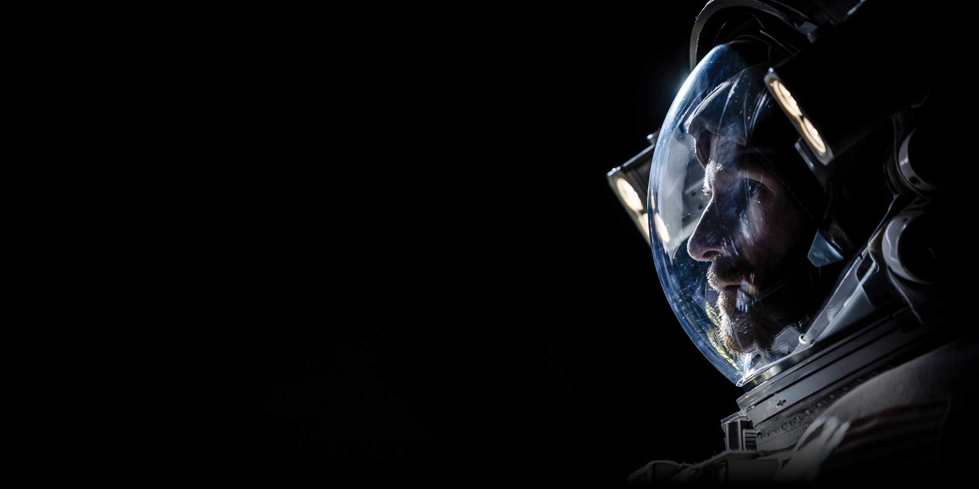 a man in an astronaut suit looking ahead on a solid black background